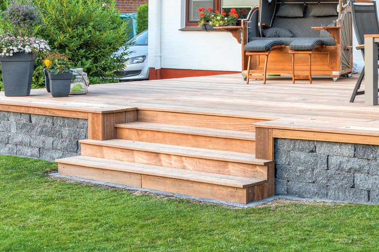 Terrasse avec marches en bois, mur et chaise de plage dans le jardin