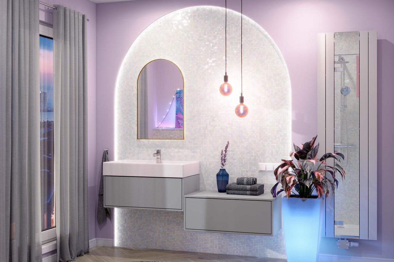Salle de bains moderne avec meuble sous vasque gris, lavabo blanc, miroir en arc et mur en mosaïque éclairé.