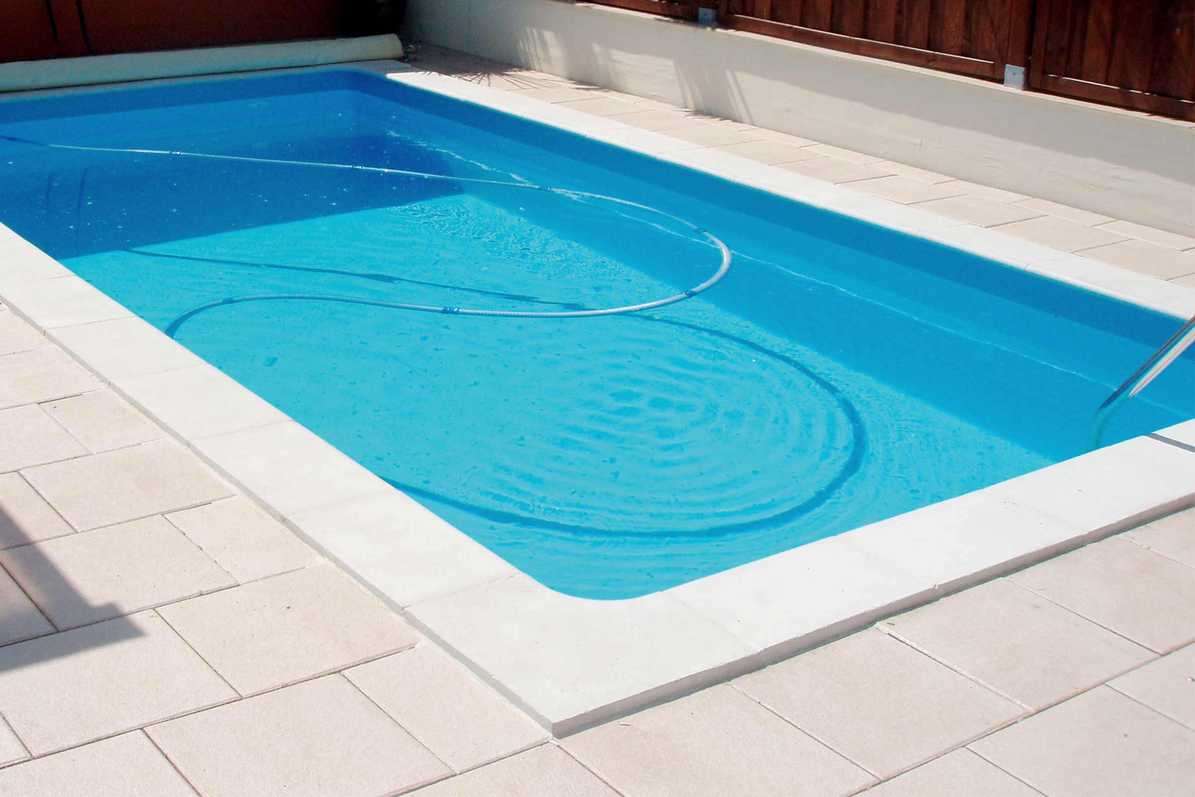 Rechteckiger Swimmingpool mit Poolreinigungsschlauch im Aussenbereich