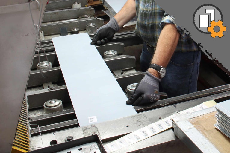 Un ouvrier positionne une plaque métallique dans une machine.