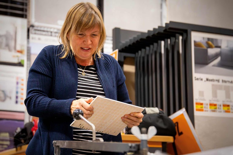 Eine Frau, die eine Fliese mit einem Fliesenschneider bearbeitet.