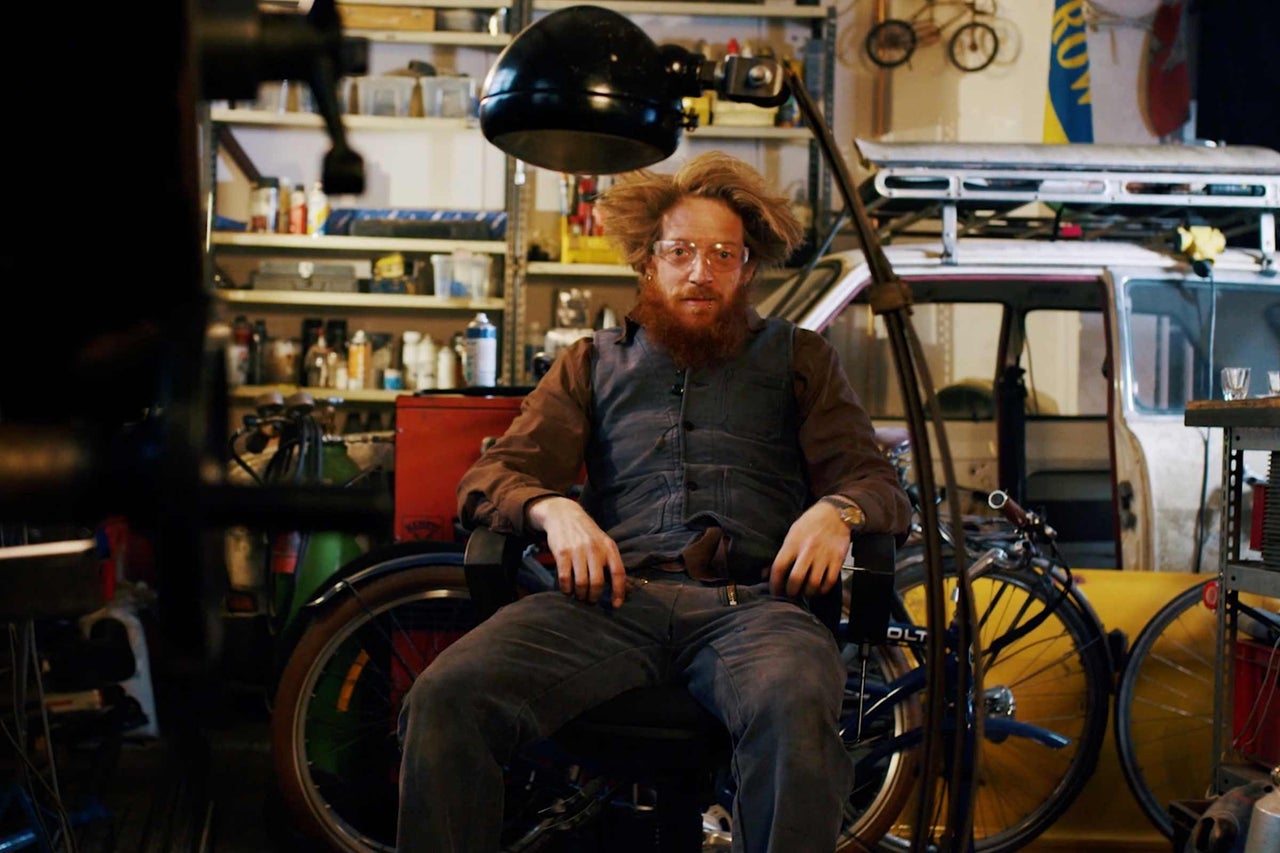 Scène d'atelier avec une personne assise, des vélos et des étagères