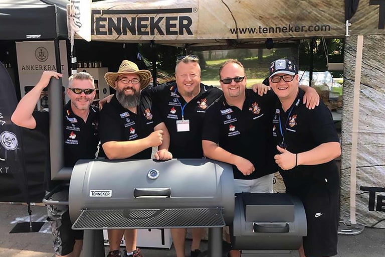 Groupe de personnes devant un barbecue Tenneker lors d'un événement.
