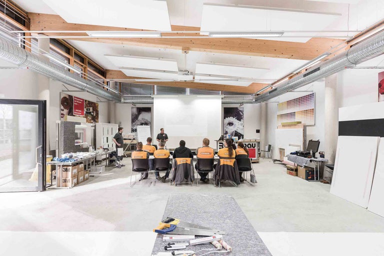 Helle Werkstatt mit Teilnehmern bei einer Schulung, Werkzeuge im Vordergrund