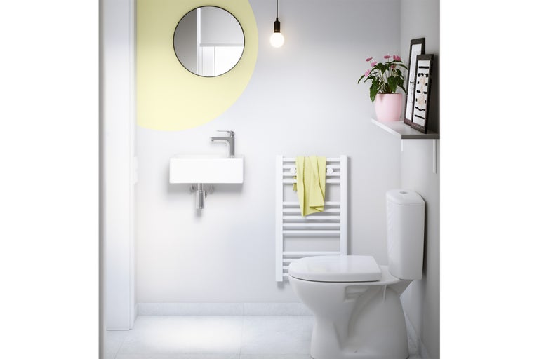 Salle de bain moderne avec toilettes, lavabo, miroir et sèche-serviettes pour une ambiance claire et organisée.