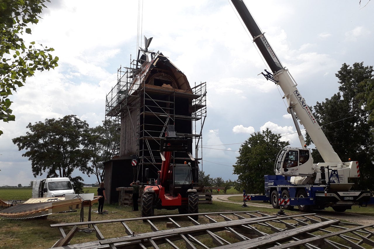 Restauration d'un vieux moulin à vent avec grue et échafaudage