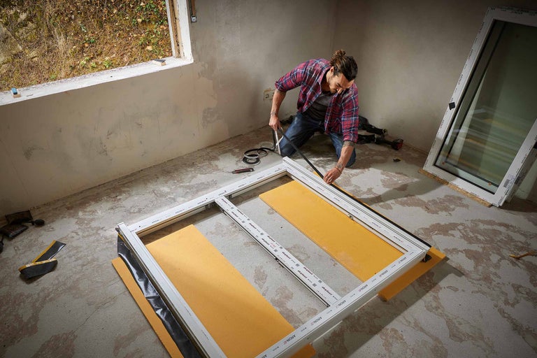 Artisan assemble un châssis de fenêtre dans un bâtiment en construction.
