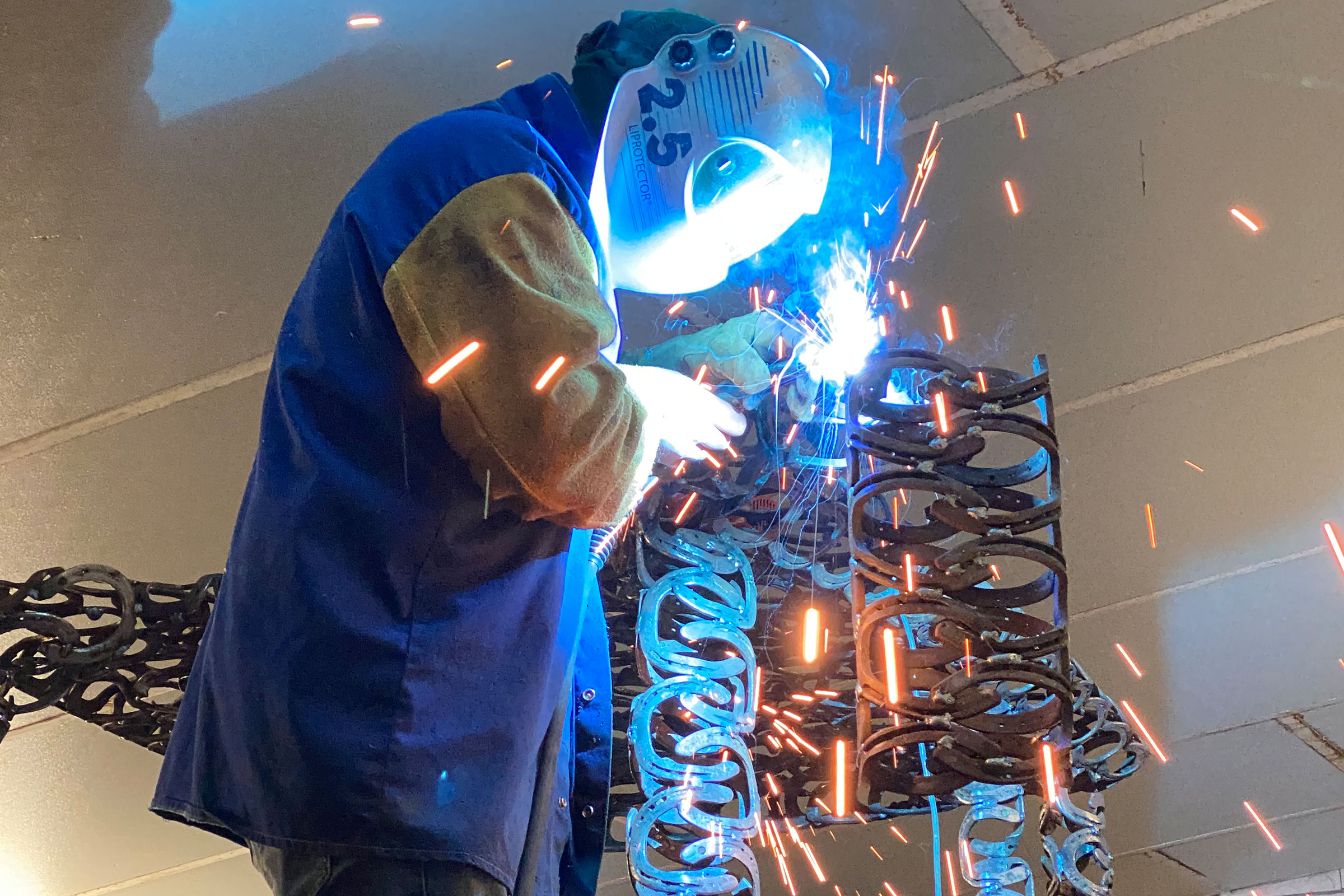 Schweißer bei der Arbeit an einer Konstruktion aus Hufeisen.