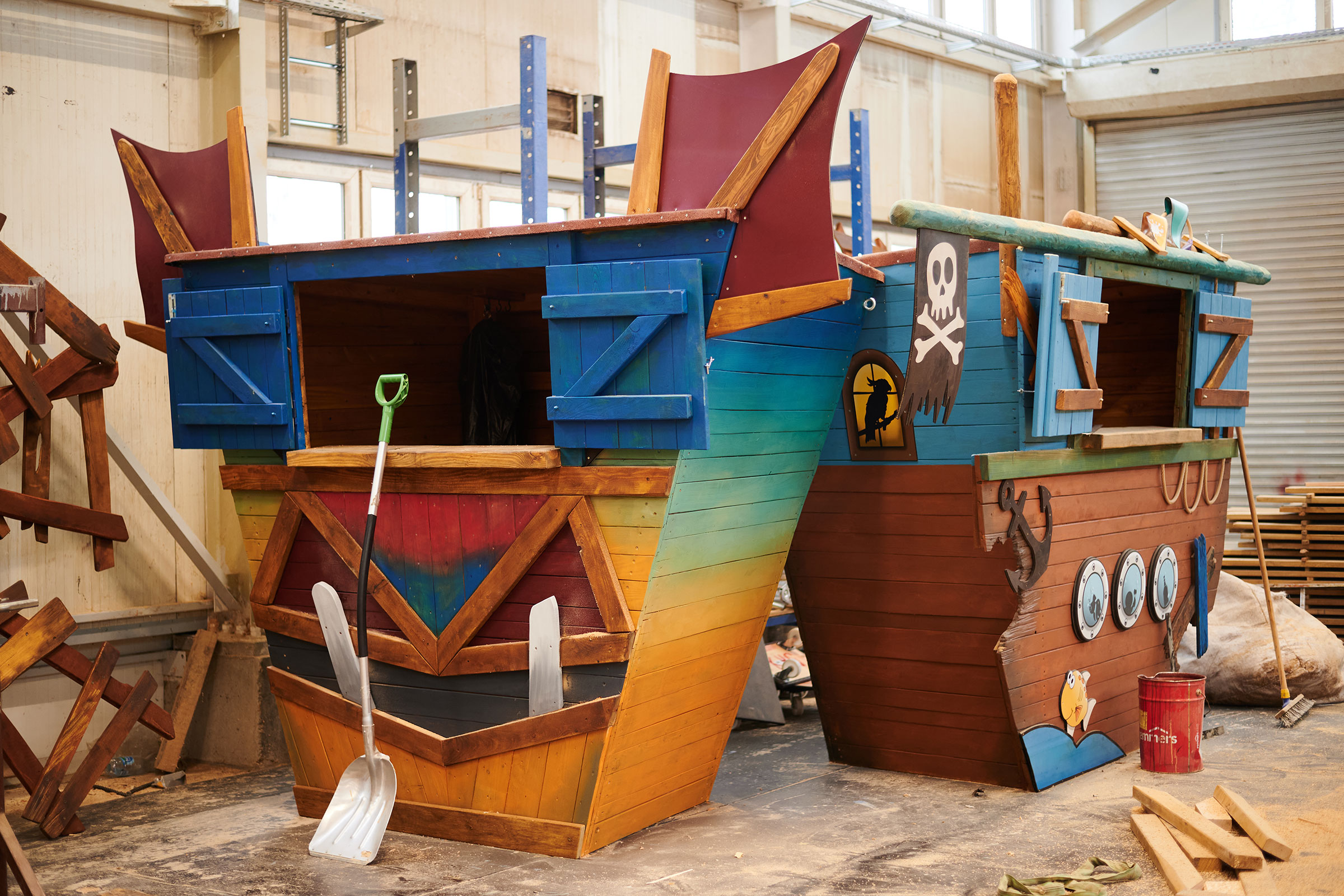 Zwei hölzerne Spielschiffe mit Piratenmotiven und Requisiten