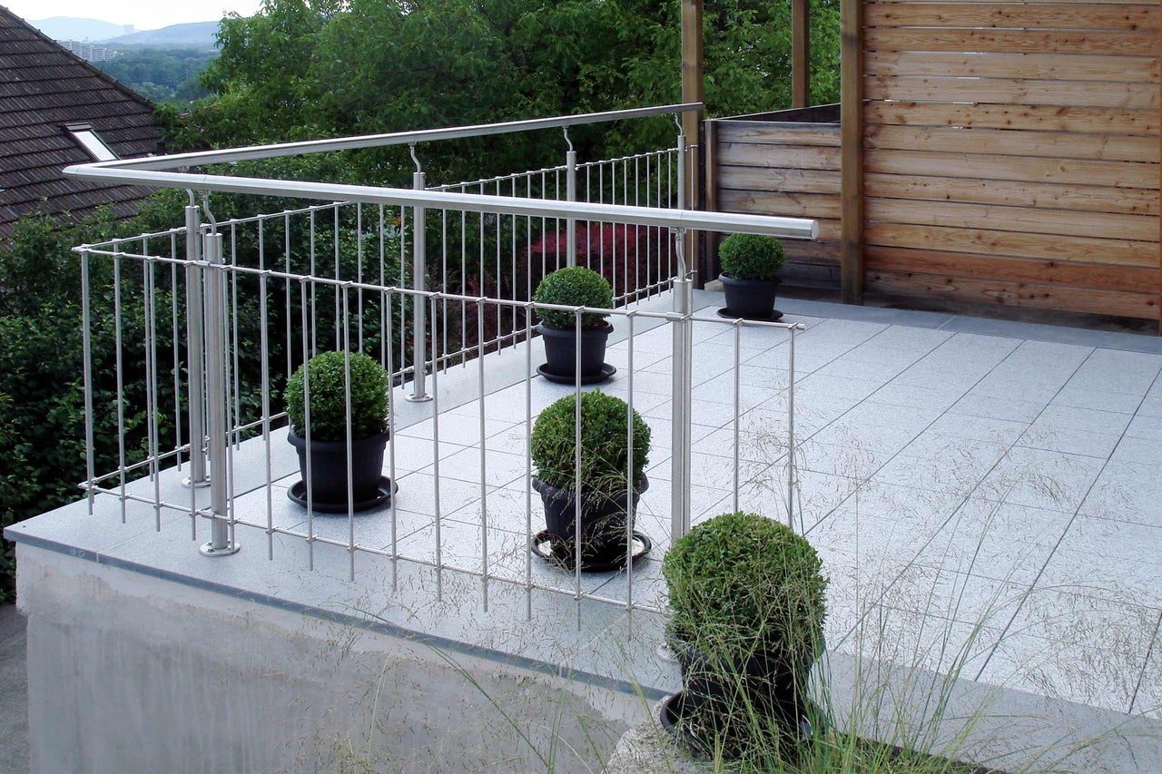 Balcon avec garde-corps en acier inoxydable, carrelage et plantes en pot