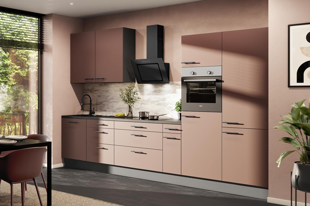 Cuisine équipée moderne vieux rose avec poignées noires, appareils électroménagers, hotte, four et crédence en marbre.