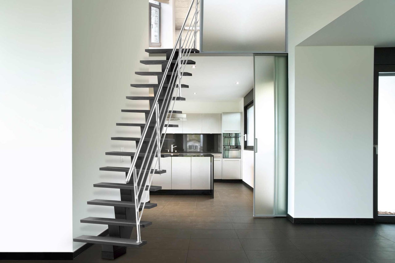 Escalier avec rampe en acier dans une pièce lumineuse avec cuisine