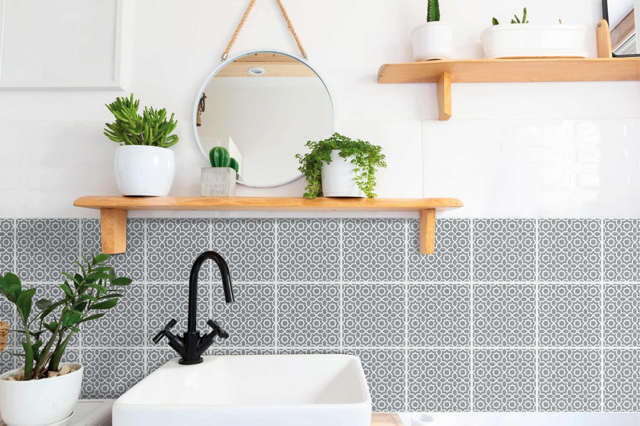 Helles Badezimmer mit Waschbecken, Armatur, Spiegel und gemusterten Fliesen