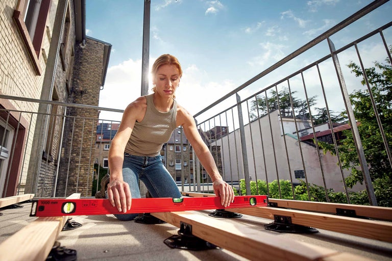 Un homme pose des planches de terrasse en bois sur une sous-construction