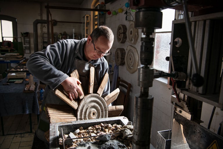 Ein Mann arbeitet mit einer Holzrad-Konstruktion in einer Werkstatt.