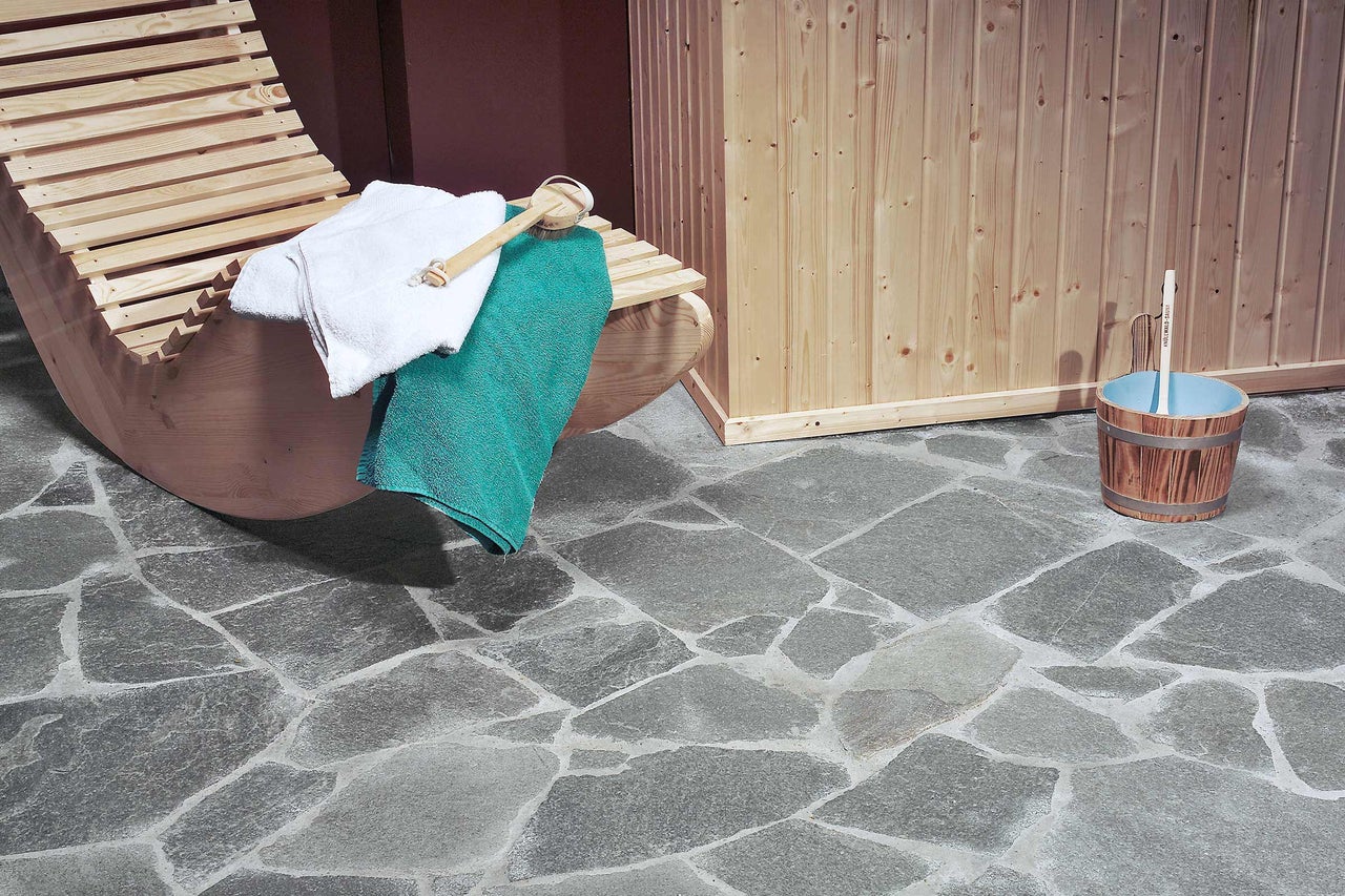 Intérieur de sauna avec chaise longue, serviettes, seau à infusion et sol en pierre