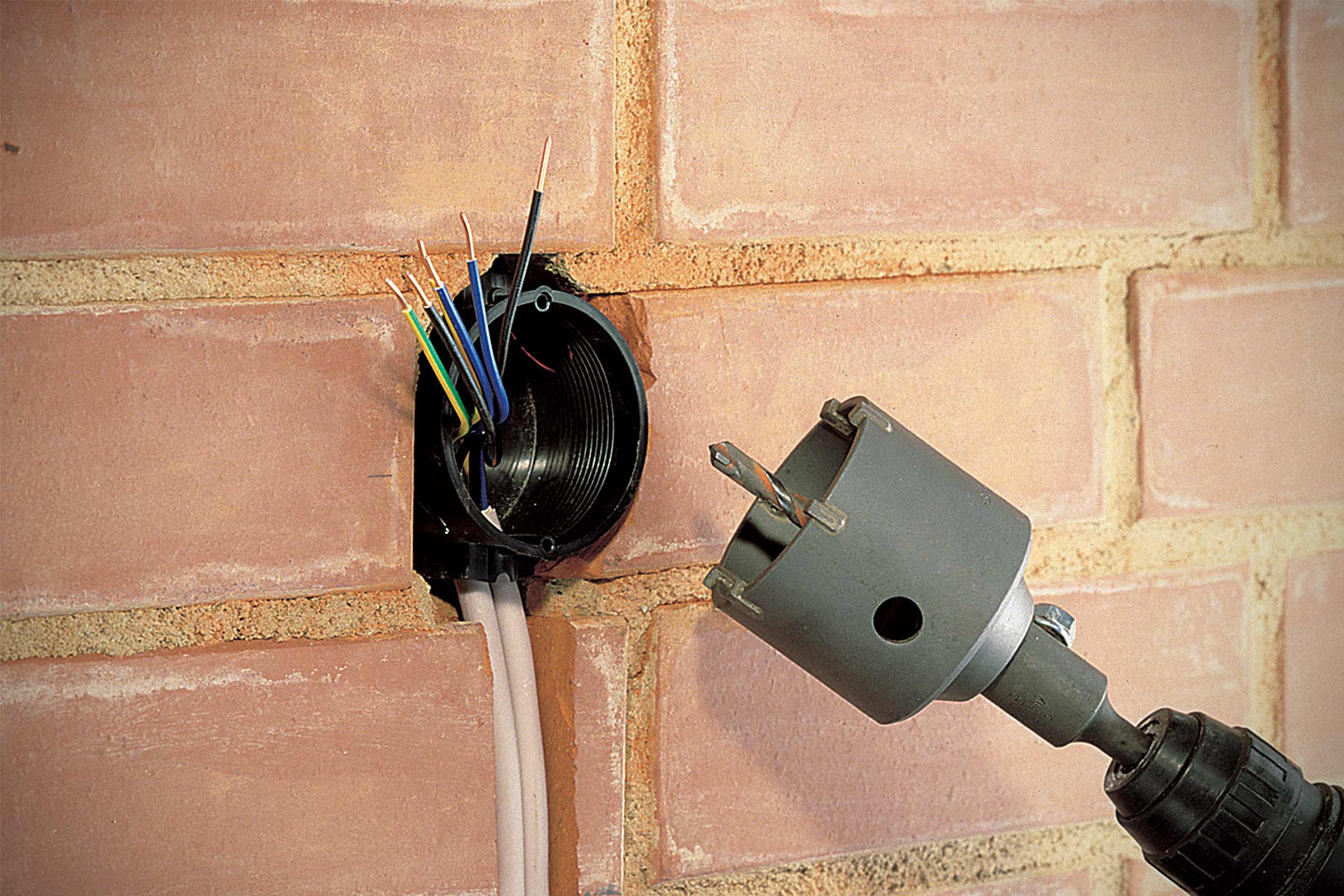 Installation électrique dans un mur de briques avec outil de scie cloche