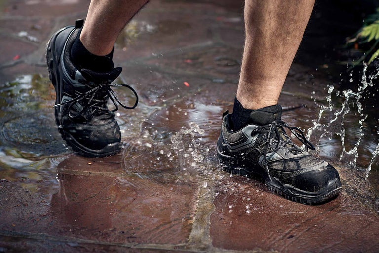 Une personne marche dans une flaque d'eau avec des chaussures de travail