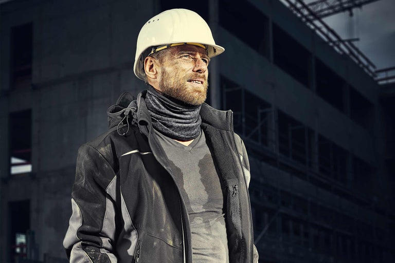 Ouvrier du bâtiment avec casque de protection, veste de travail et tissu multifonctionnel sur un chantier