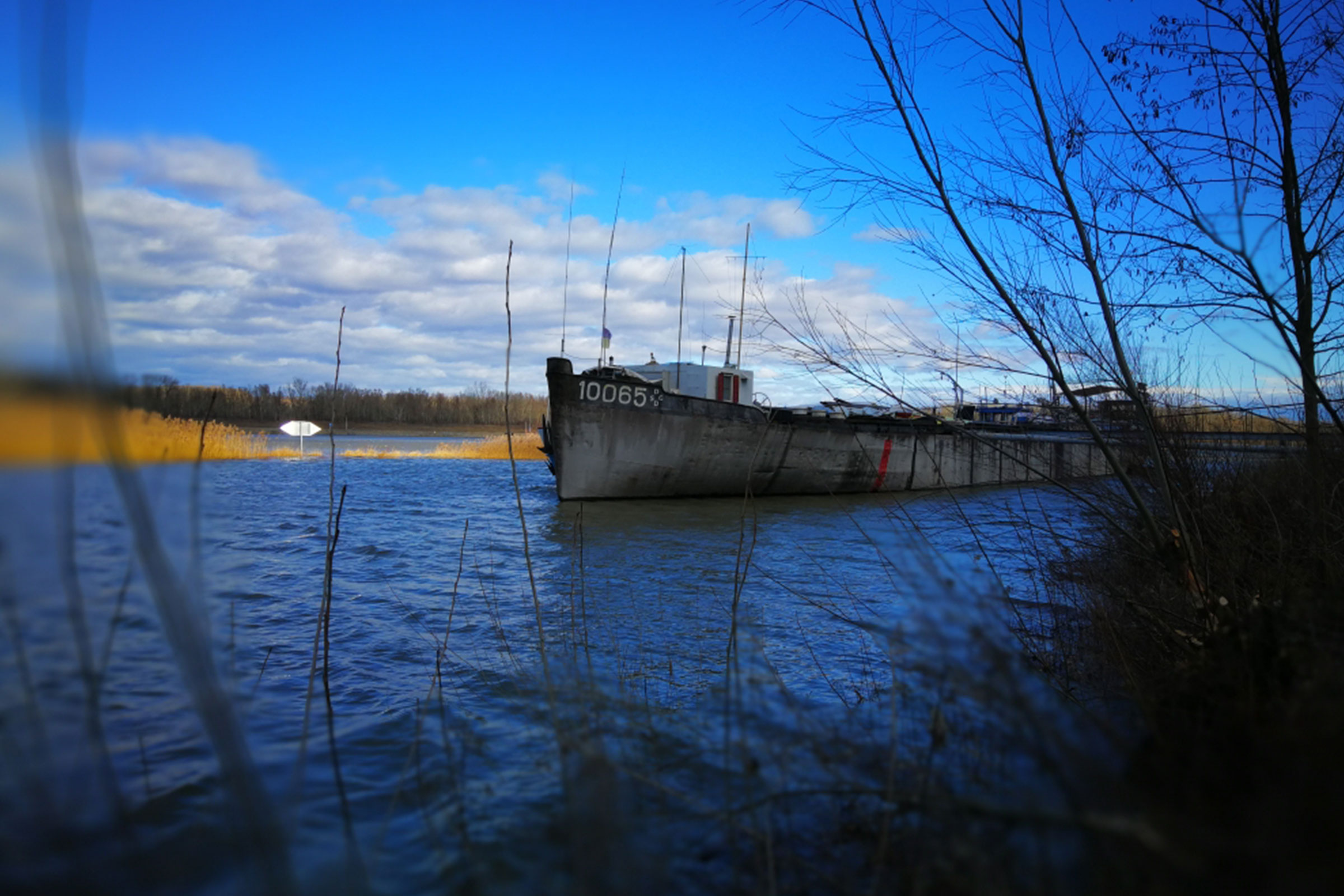 Ein Schiff liegt im Wasser unter einem blauen Himmel.