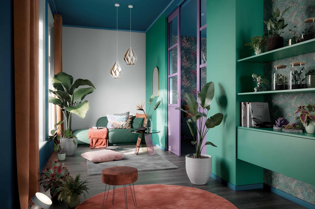 Un salon avec un canapé, une table, un tabouret, des tapis, des plantes et des éléments décoratifs.