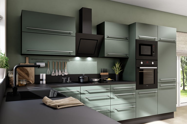 Cuisine équipée moderne vert mat avec plan de travail noir, four, micro-ondes, hotte et poignées argentées.