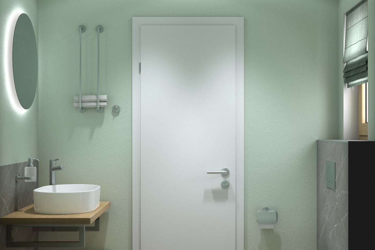 Salle de bain moderne avec murs vert clair, porte blanche, vasque ronde sur plateau en bois, miroir rétroéclairé et accessoires.