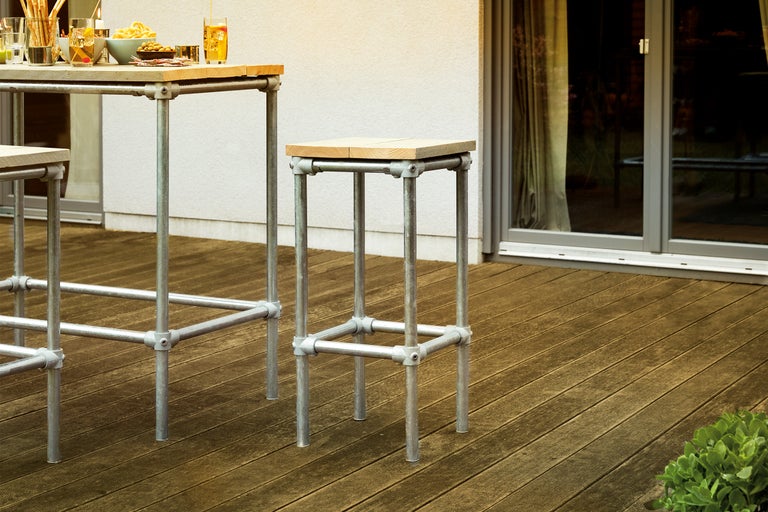 Tabouret de bar et table de bar avec structure en tube d'acier et plateau en bois sur une terrasse