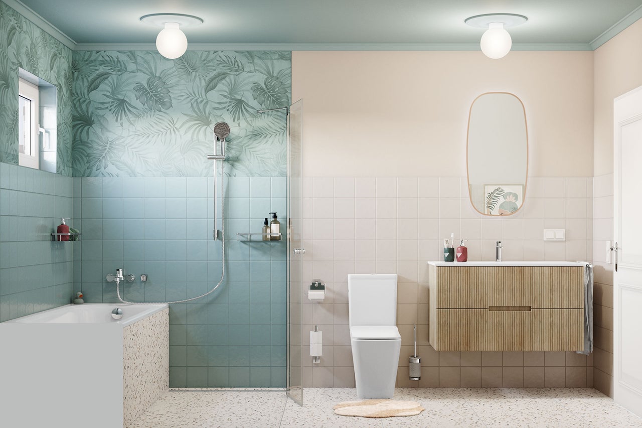 Salle de bains moderne et lumineuse avec carrelage bleu et beige, baignoire aspect terrazzo, douche à l'italienne, WC blanc et meuble en bois avec miroir.