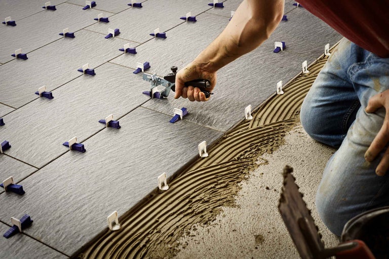 Fliesenleger bei der Arbeit mit Nivelliersystem und Fliesen