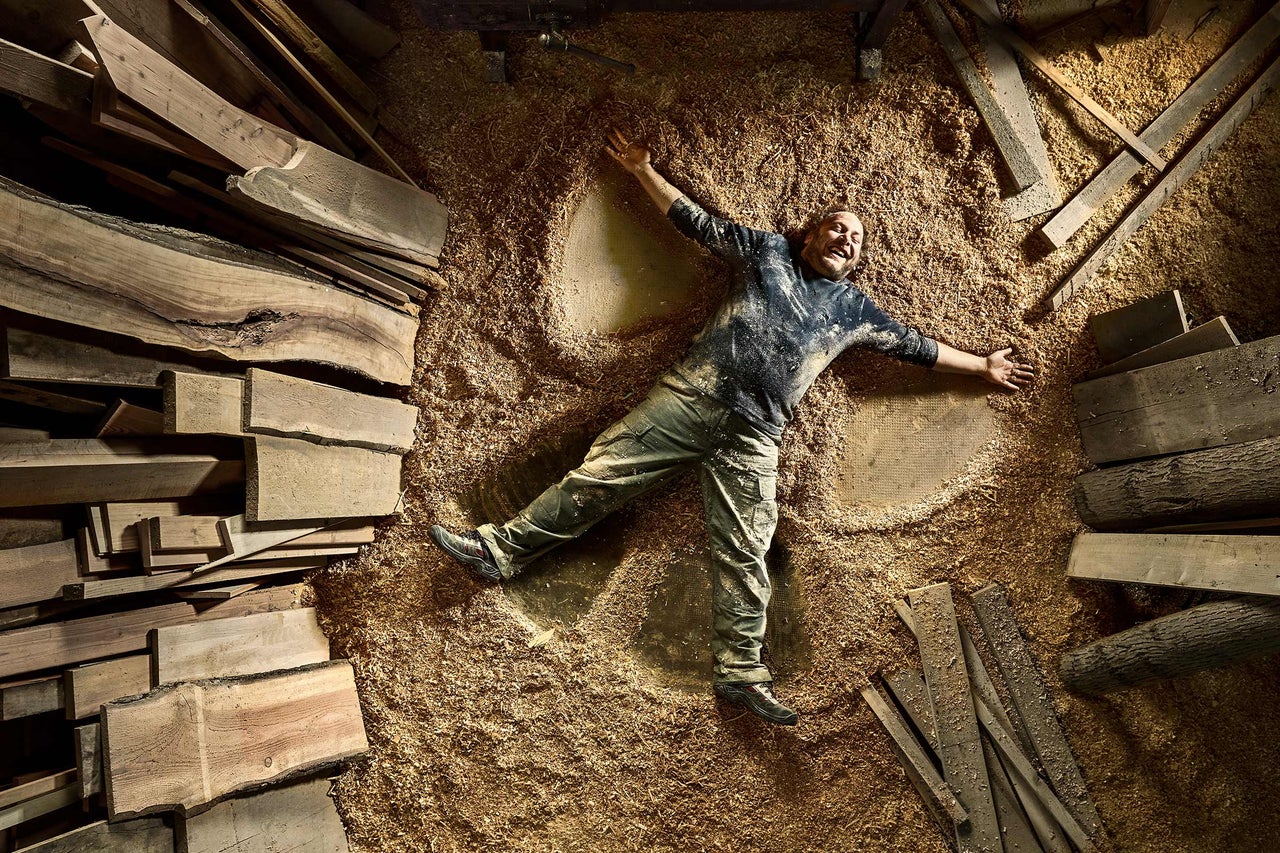 Homme allongé dans des copeaux de bois entre des planches de bois