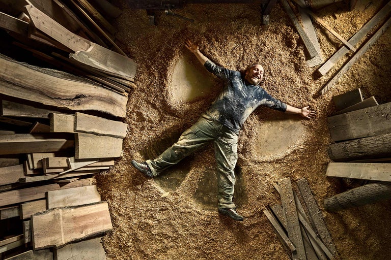 Homme allongé dans des copeaux de bois entre des planches de bois