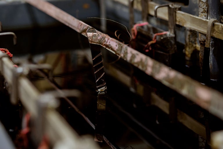 Pièce métallique suspendue à un rail métallique dans un liquide