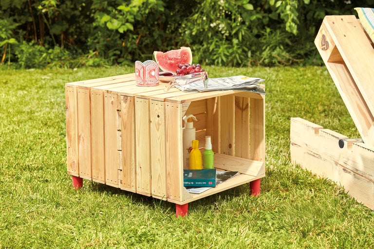 Scène de jardin avec une table basse en caisses de bois, des boissons et des collations sur une pelouse