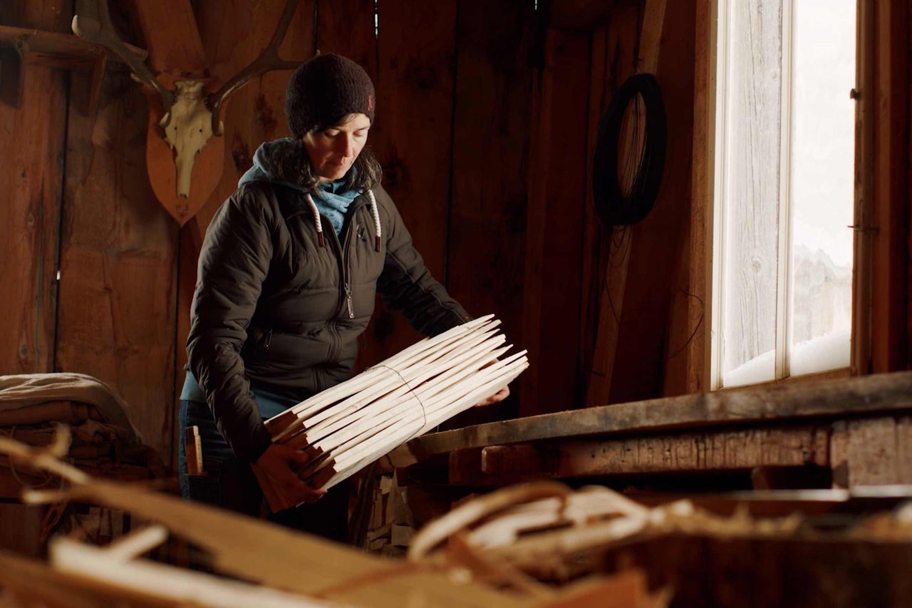 Femme tenant un faisceau de bâtons en bois dans un atelier