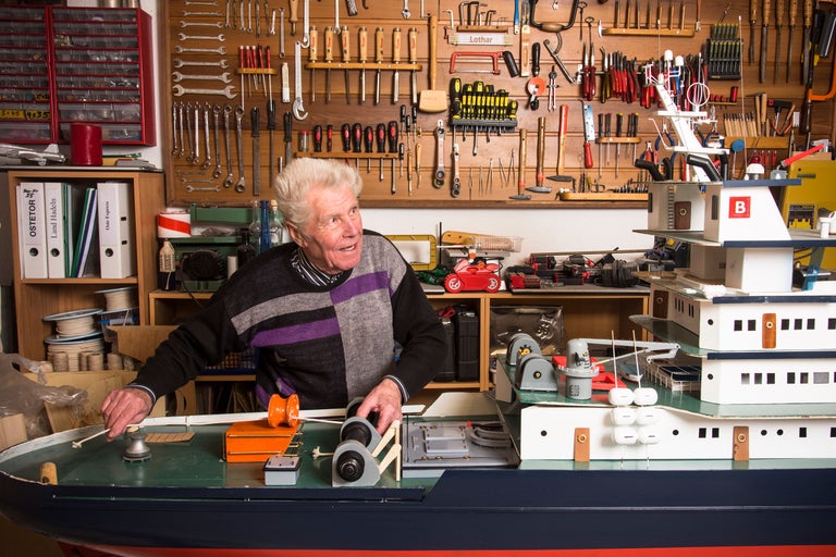 Ein Mann baut ein Schiffsmodell in einer Werkstatt mit Werkzeugen.