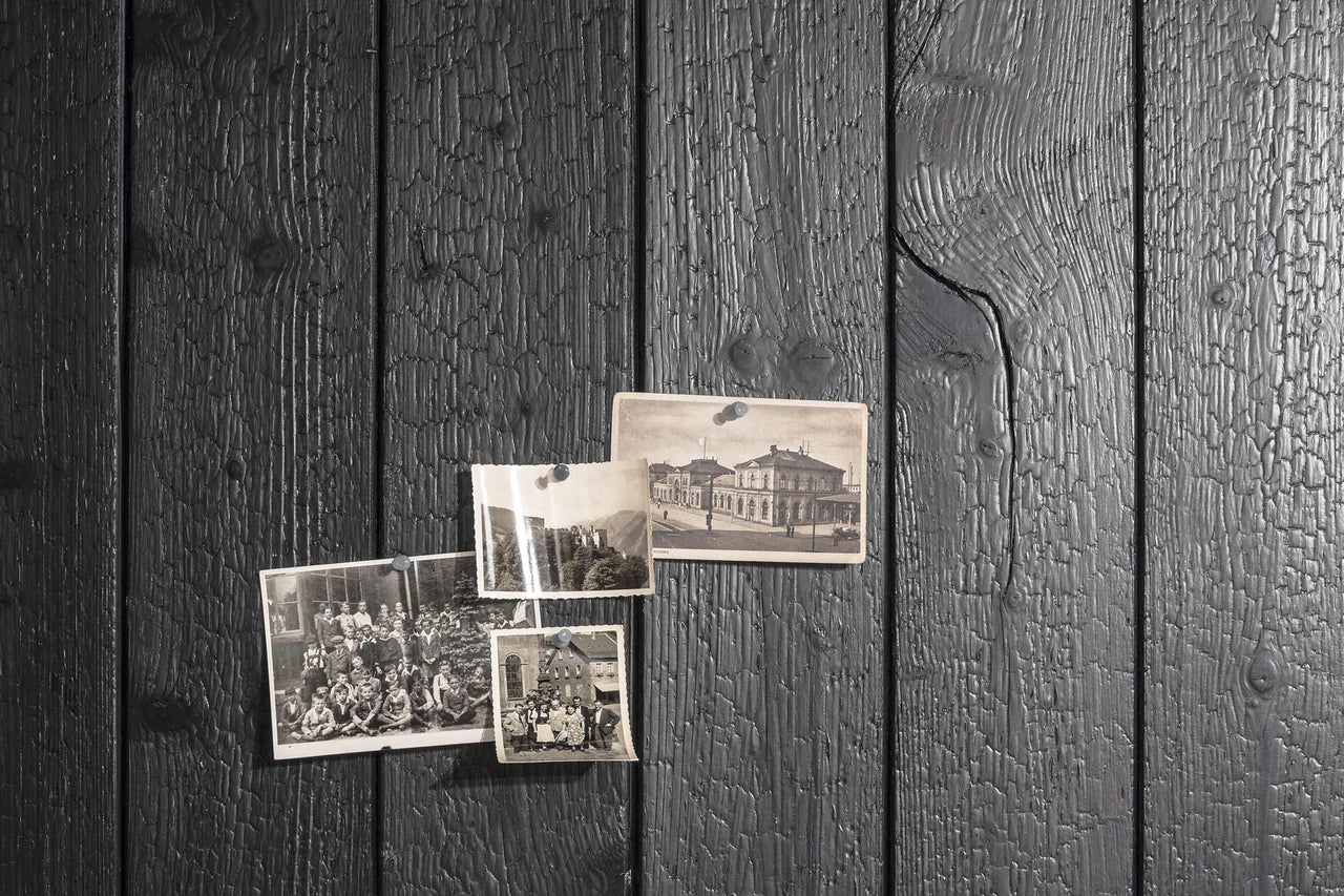 Lambris en bois sombre avec des photos historiques, fixées par des punaises.