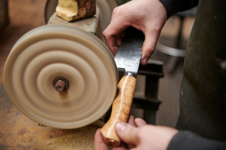 Messer mit Holzgriff wird an einer Poliermaschine geschliffen