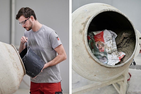 Un homme portant des lunettes de protection verse le contenu d'un seau dans une bétonnière.