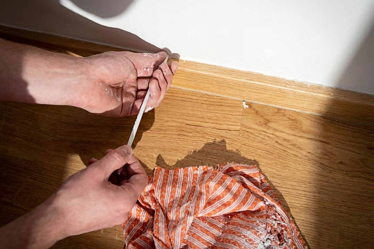 Nettoyage d'une plinthe avec un couteau à mastic et un chiffon