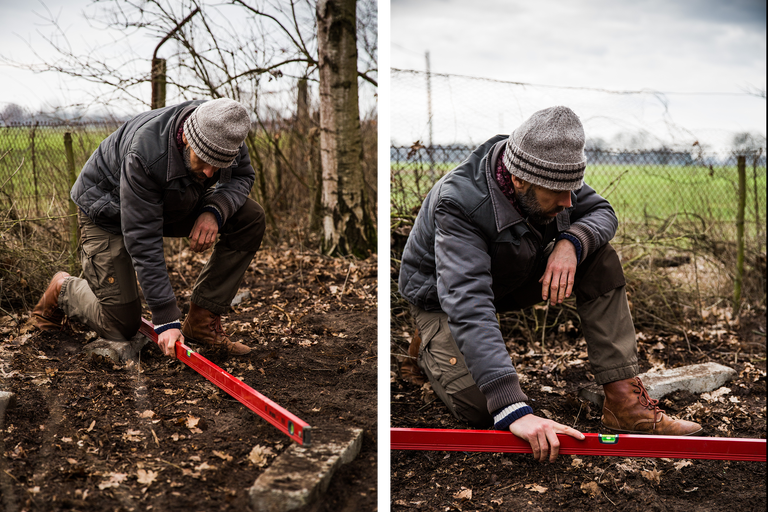Mann prüft mit einer Wasserwaage die Ausrichtung von Pflastersteinen im Garten.