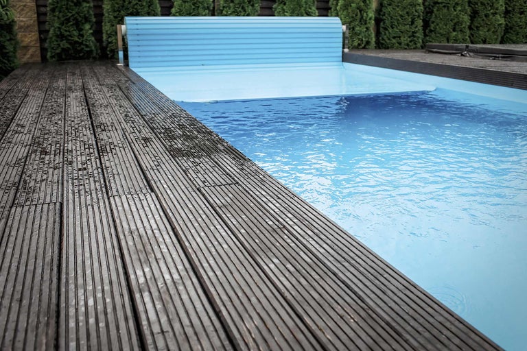 Piscine avec terrasse en bois et couverture