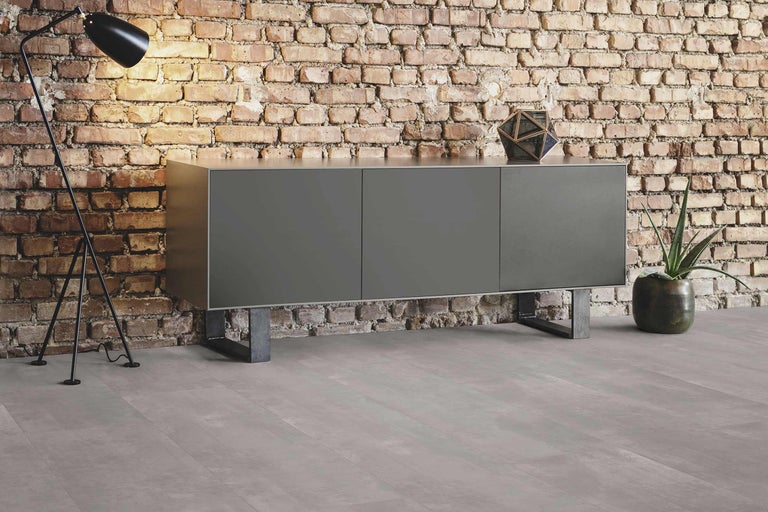 Salon moderne avec buffet, lampadaire et plante d'intérieur devant un mur en briques