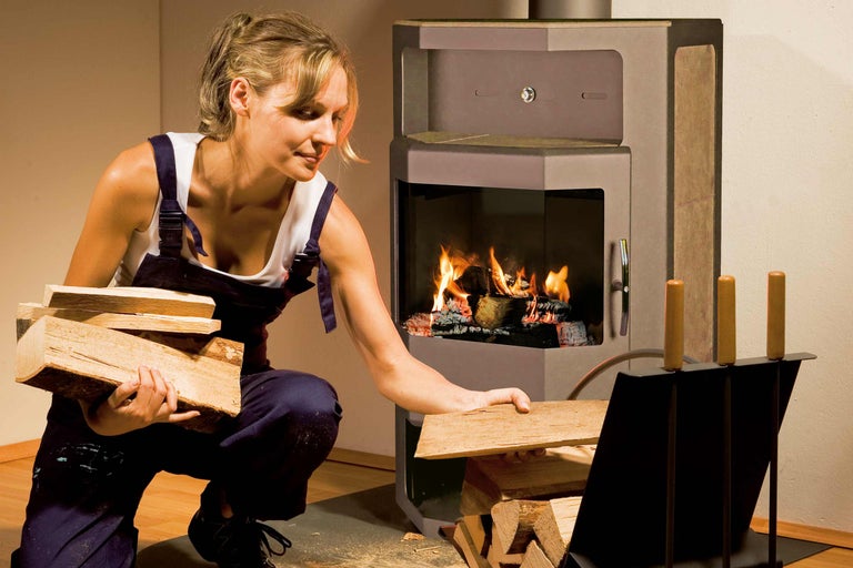 Femme plaçant du bois dans un poêle à bois