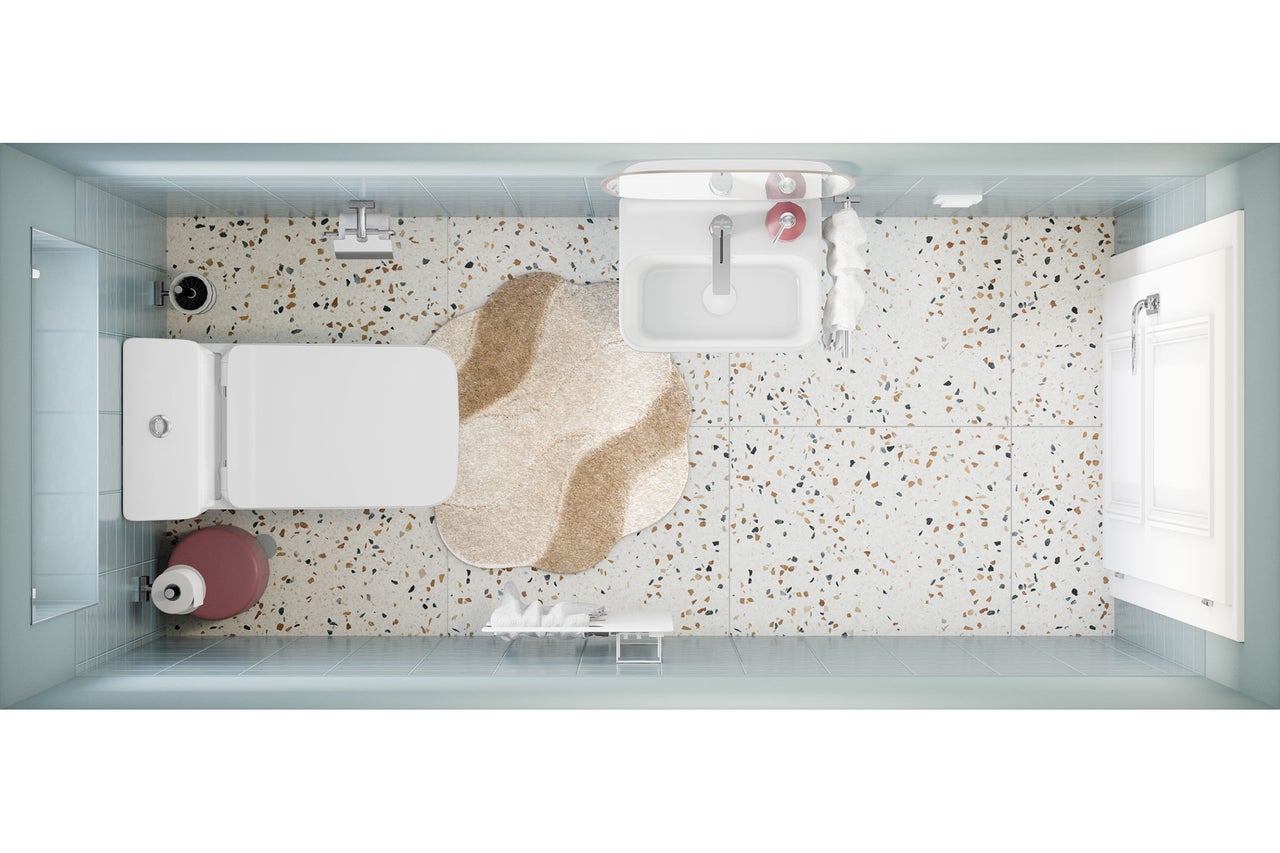 Vue de dessus d'une salle de bains lumineuse et moderne avec sol en terrazzo, carrelage bleu clair, lavabo, toilettes et tapis de forme irrégulière.