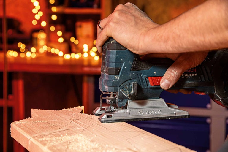 Une scie sauteuse coupe une planche de bois. Logo Bosch.