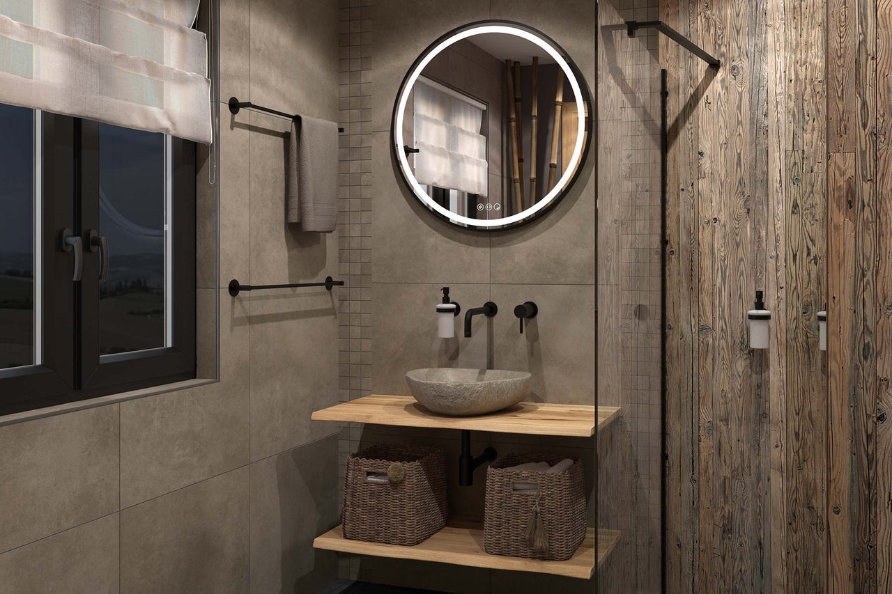 Salle de bains moderne avec miroir LED rond, vasque à poser en pierre sur des étagères en bois, robinetterie murale et carrelage aspect pierre.