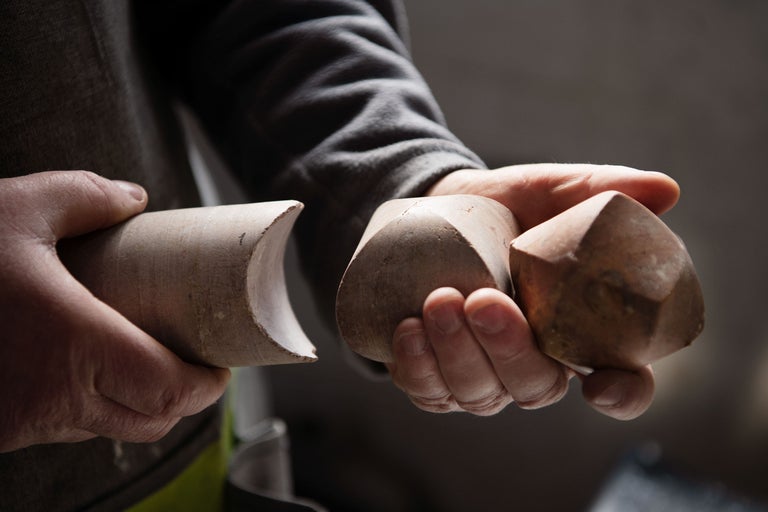 Une personne tient des formes de vis en bois dans sa main.