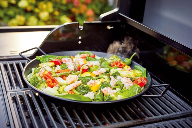 Légumes et crevettes dans un plat à griller sur un barbecue