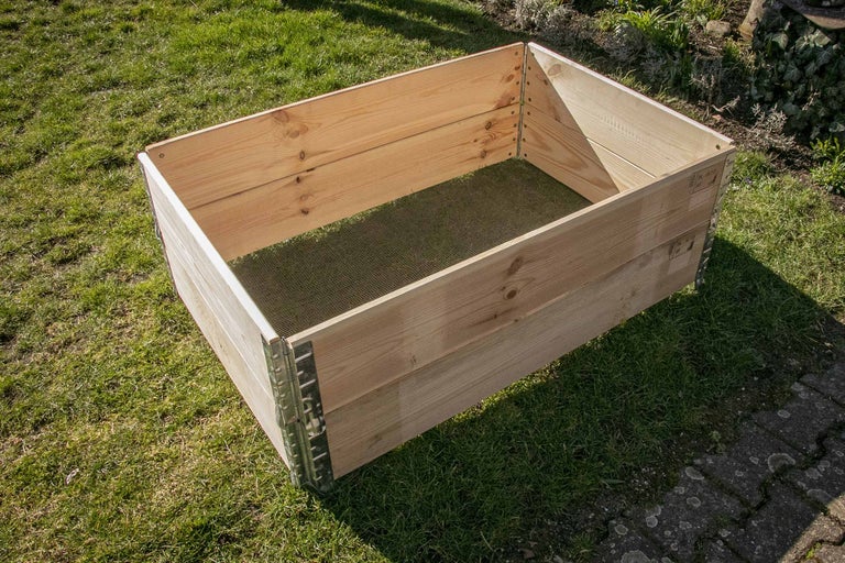 Jardinière surélevée en bois avec coins en métal sur une pelouse